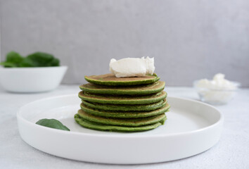 Spinach pancakes with cream cheese on a light gray background, close-up. The concept of proper nutrition, wholesome food