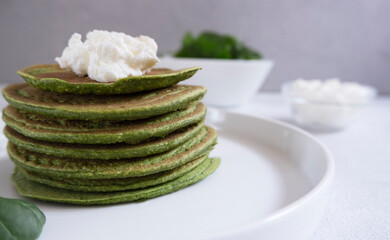 Spinach pancakes with cream cheese on a light gray background, close-up. The concept of proper nutrition, wholesome food