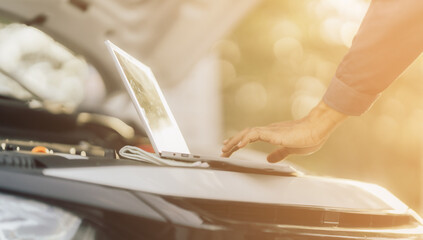 Young mechanic opens the bonnet to inspect the engine for damage and does professional maintenance. He puts on his uniform and inspects.