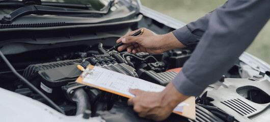 A car mechanic checks and maintains the engine for the customer. The car hood and master inspector replace the damaged parts in the car while checking the operation of the car. repair concept service