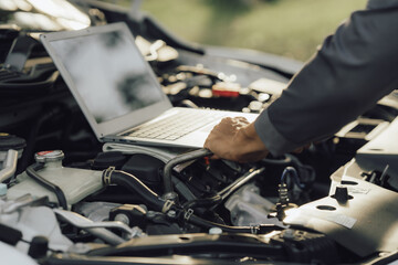 Fototapeta premium Young mechanic opens the bonnet to inspect the engine for damage and does professional maintenance. He puts on his uniform and inspects.