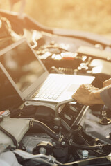 Young mechanic opens the bonnet to inspect the engine for damage and does professional maintenance. He puts on his uniform and inspects.