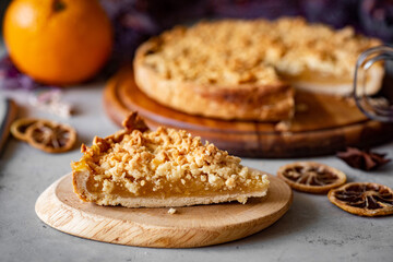 A piece of orange pie on a plate and an orange pie in the background on a plate. Pie with orange filling for breakfast. Close-up.
