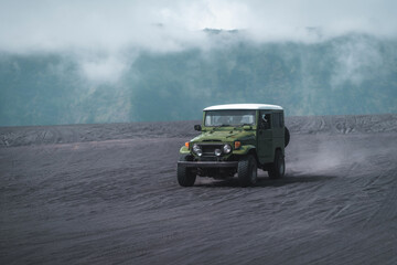 Obraz na płótnie Canvas Travelling jeep driving trip in Bromo mount volcano territory. Vehicle journey in Semeru savanna field