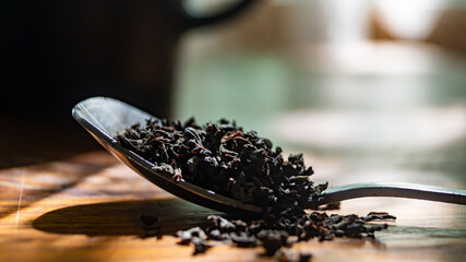 Tea in a spoon. Loose black tea. Black tea in an iron spoon. Tea in a spoon on the table