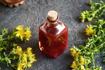 Obraz na płótnie Canvas A bottle r of St. John's wort oil with fresh Hypericum blossoms