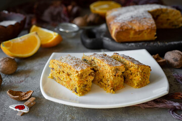 Sweet dessert: slices of pumpkin pie with orange for breakfast on a white plate on a gray background. Close-up
