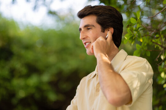 Closeup of handsome young man touching his wireless earphone