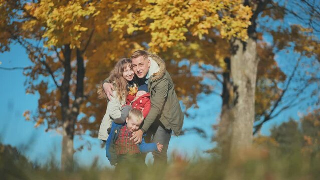 A young, happy family in the park sprinkled with leaves.