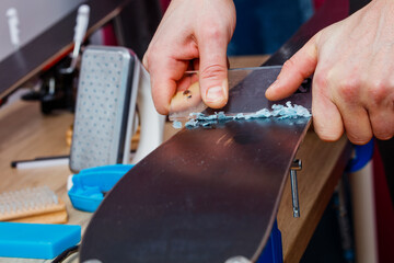 Hand scrape off wax from ski base before polishing