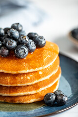 Fresh American Pancakes with blueberries and maple syrup on blue plate