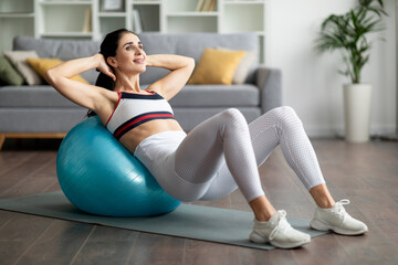 Athletic young woman doing exercises with fit ball at home