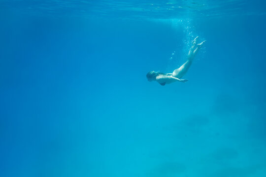 Woman swimming in open sea. Close up underwater photo. Diving girl in open water.