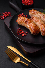 Delicious juicy grilled sausages with salt, spices and herbs on a ceramic plate