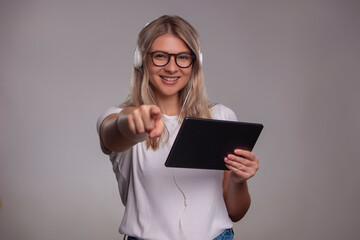 Portrait of woman holding tablet and looking at camera, isolated on gray background