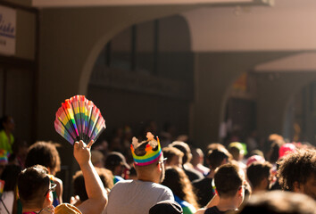 Mãos segurando leque com as cores da bandeira símbolo do orgulho LGBT+.  27ª Parada do Orgulho LGBT+ Avenida Paulista, São Paulo, Brasil. - obrazy, fototapety, plakaty