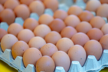 Stacked in layers of fresh chicken eggs in the tray for sale in the market stall, A pile of eggs in brown paper panels in the kitchen for cooking.