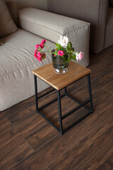 Shabby wooden table with chairs and vase located near comfortable couch against light walls with decorations in modern apartment. High quality photo