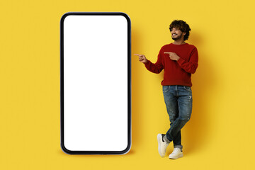 Handsome eastern guy pointing at huge cell phone, mockup