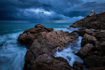 amanecer con nubes de colores en la playa con rocas