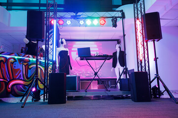 Dj controller on stage for discotheque in empty nightclub with no people. Electronic musician console equipment, loudspeakers and spotlights for live music concert in dark club.