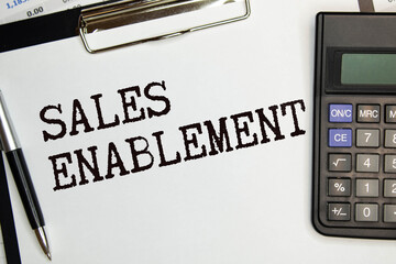 paper money, glasses, calculator, magnifying glass and paper with the word SALES ENABLEMENT.