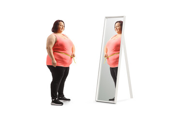 Young overweight woman measuring her waist in front of a mirror