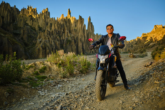 latin man on his motorcycle with a sunglasses posing at sunset in the valley of the animas in La Paz bolivia