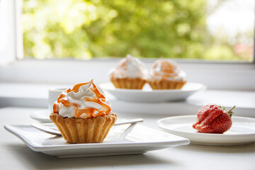 cake with cream on white plates on the table against the window. set . selective focus 
