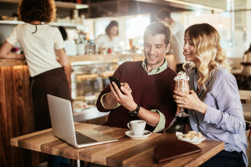 Young couple using a smart phone in a cafe while enjoying a nice cup of coffee
