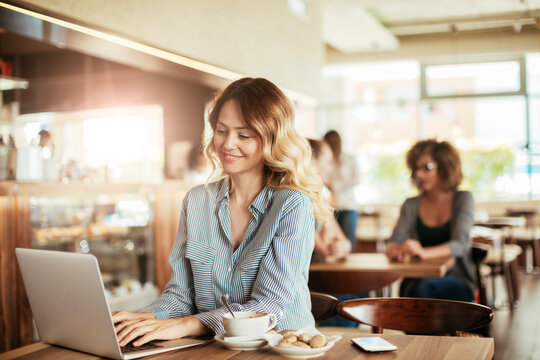 Young woman having a cup of coffee in a cafe while using a laptop