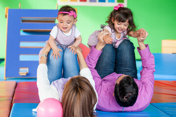 Young parents playing with their daughters. Early stimulation for toddlers and children concept.