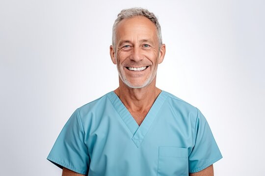 Portrait of senior male doctor smiling at camera while standing against white background