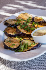 Plateful of Fried Sliced Aubergine or Eggplant Covered with Fresh Flat Leaf Parsley and Served with Pureed Roasted Garlic
