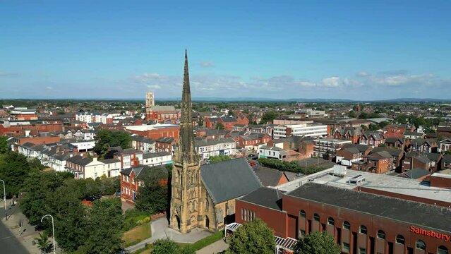 Southport, Lancashire, UK, June 24, 2023; Mid-level aerial fly by clip video footage of St George's URC Church with tall spire on Lord Street in Southport, England