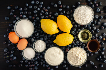 Blueberry Muffins with Lemon Glaze on a Dark Wood Background: Fresh blueberries, lemons, and other raw ingredients on a rustic wooden background
\