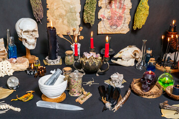 Occult and esoteric witchcraft still life. Halloween background with magic objects. Black candles, skull, crystal stones, and potions vials for witch. Mystic witchery background with dry weeds.