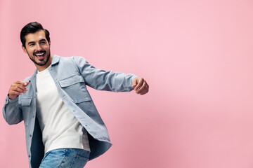 Stylish brunette man with beard happiness open mouth jumping and running spreading his arms on a pink background in a white T-shirt and jeans smile and joyful emotion on his face, copy space
