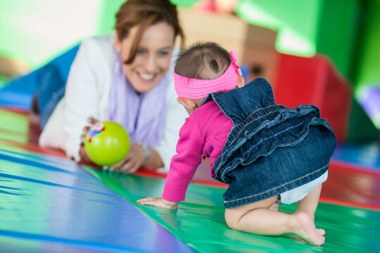 Beautiful ten months baby girl playing with her mom. Early stimulation for toddlers concept.