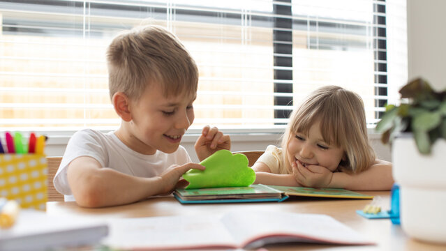 Brother and sister together amicably read an educational book. The concept of a happy childhood.