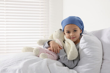 Childhood cancer. Girl with toy bunny in hospital