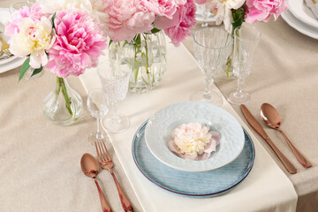 Stylish table setting with beautiful peonies and golden cutlery