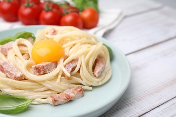 Delicious pasta Carbonara with egg yolk on white wooden table, closeup