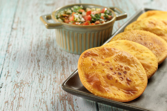 Sopaipillas of pumpkin or squash in rectangular plate on wooden table and bowl with pebre with copy space for typical chilean food concept