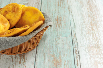 Sopaipillas of pumpkin or squash in a round basket with gray cloth, on a wooden table, with copy space. Typical Chilean food concept