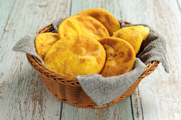 Sopaipillas of pumpkin or squash in round basket with gray cloth, on wooden table in the center. typical Chilean food concept