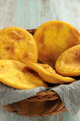 Sopaipillas of pumpkin or squash in a round basket with gray cloth, on a wooden table, vertically, with copy space. Typical Chilean food concept