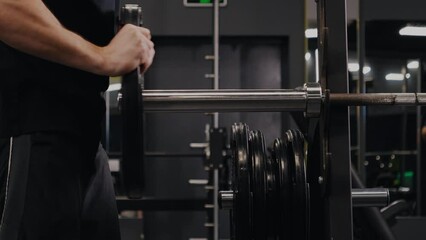 Weights Gym, Man Barbell, Man Weights. In gym, man assembles his barbell by placing weights on it.