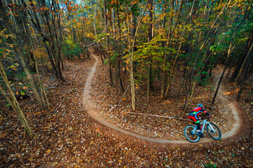A mountain biker zooms around a curving singletrack trail in a North Carolina forest in autumn