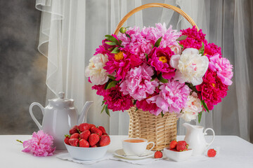 Obraz na płótnie Canvas Summer breakfast concept. Fresh strawberries in a bowl on the table and a bouquet of peonies in a vase